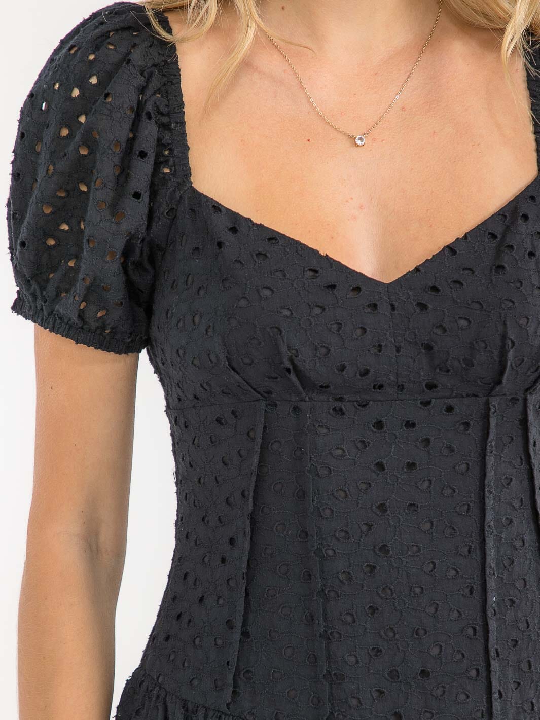 Black dress with eyelet details on a white background