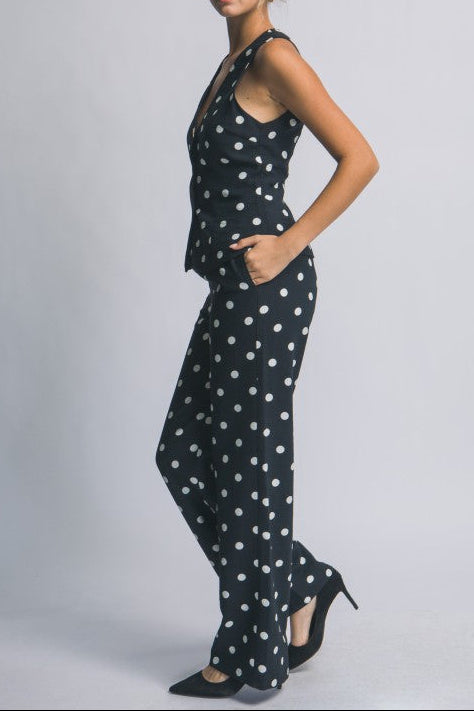 Woman wearing a black polka dot jumpsuit on a plain background