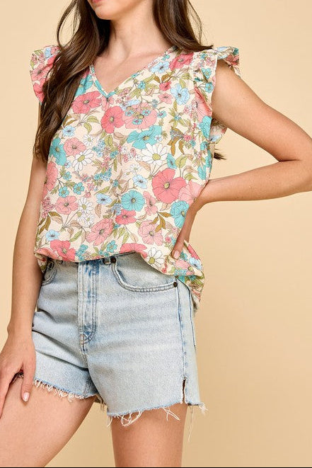Woman wearing a floral top and denim shorts on a beige background
