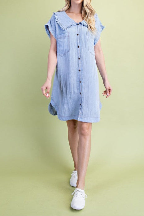 Woman wearing a blue dress with ruffled sleeves against a green background