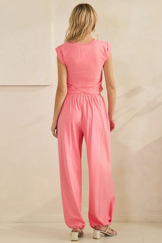 Woman wearing a pink jumpsuit against a beige background