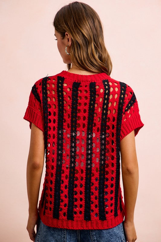 Red and black patterned top worn by a person on a pink background