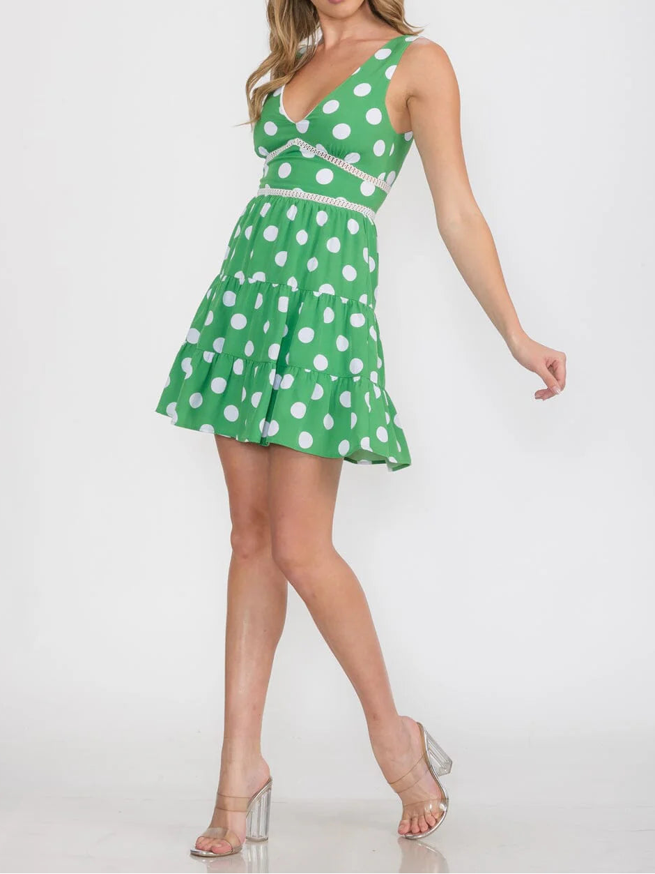 Woman wearing a green dress with white polka dots on a white background