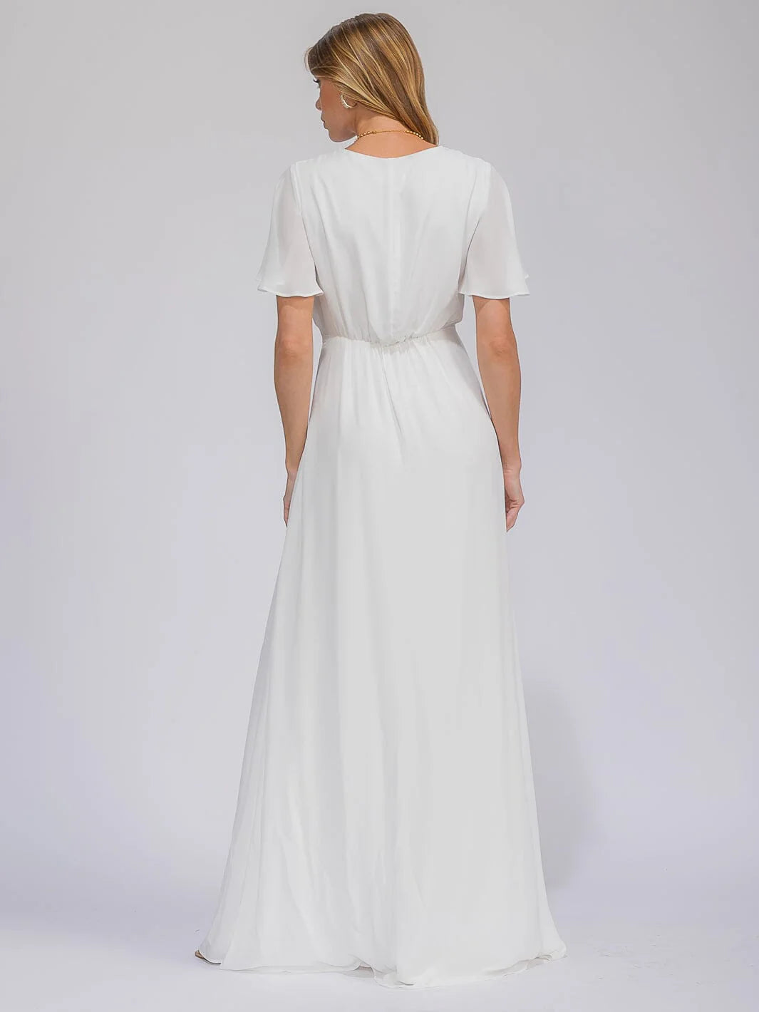 Woman wearing a white dress on a plain background