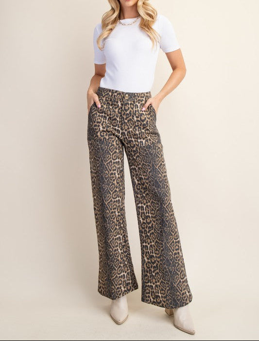 Woman wearing leopard print pants and a white top on a beige background