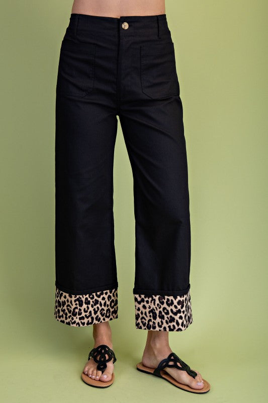 Black pants with leopard print cuffs on a green background