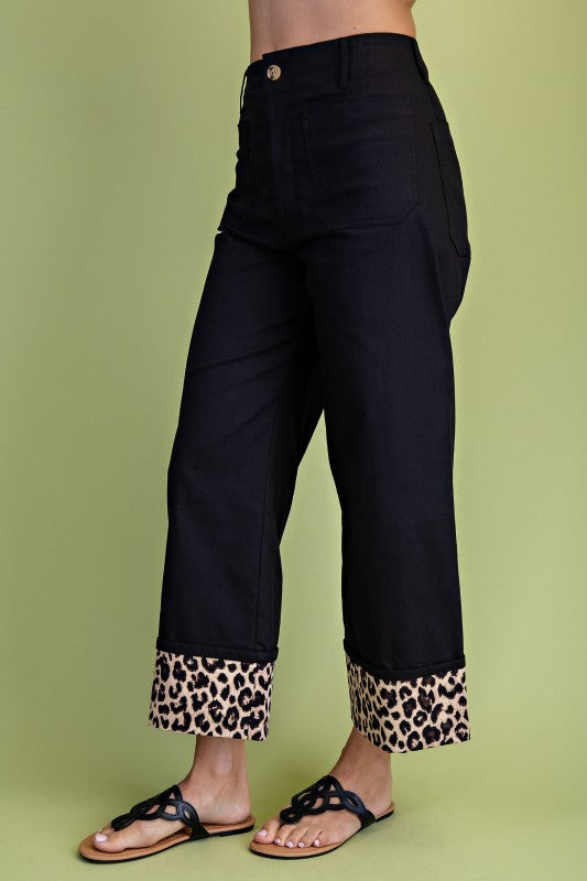 Black pants with leopard print cuffs on a green background