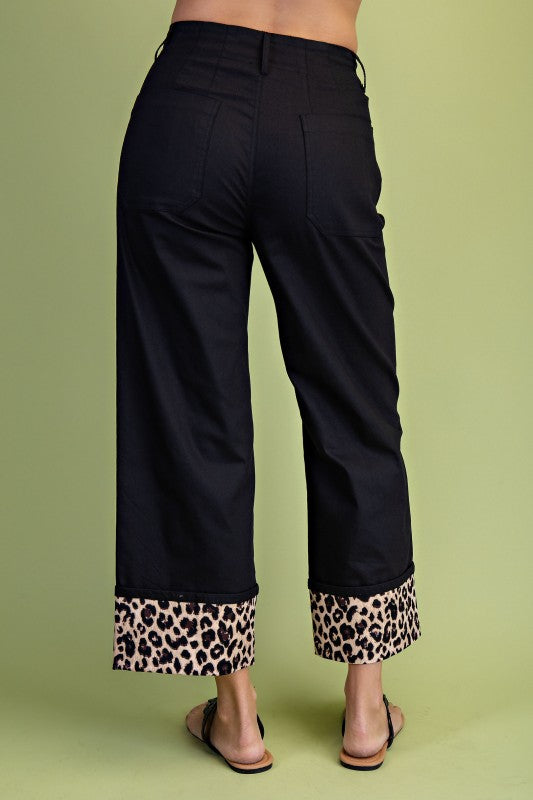 Black pants with leopard print cuffs on a green background
