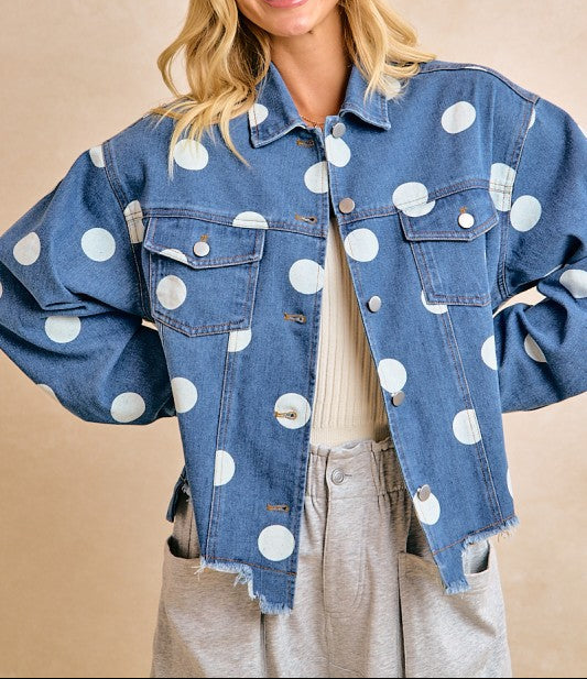 Woman wearing a blue denim jacket with white polka dots on a beige background