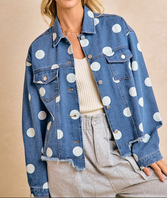 Woman wearing a denim jacket with white polka dots, beige hat, and light pants on a beige background