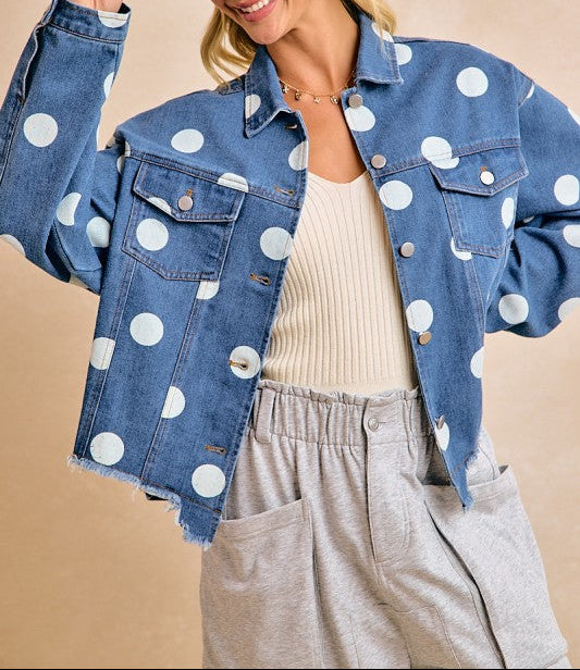 Woman wearing a polka dot denim jacket and beige hat against a beige background