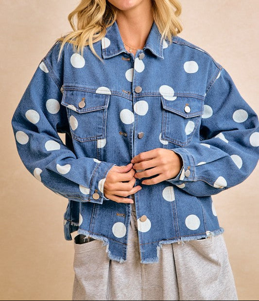 Woman wearing a blue denim jacket with white polka dots on a beige background