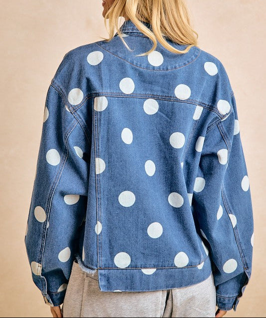 Woman wearing a blue denim jacket with white polka dots on a beige background