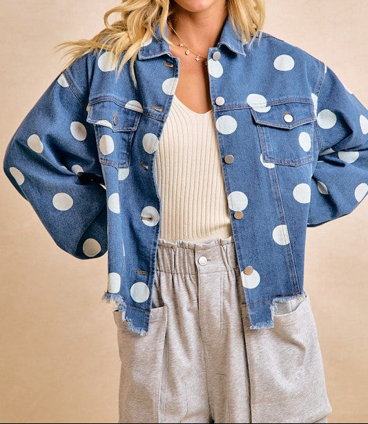 Woman wearing a blue denim jacket with white polka dots on a beige background