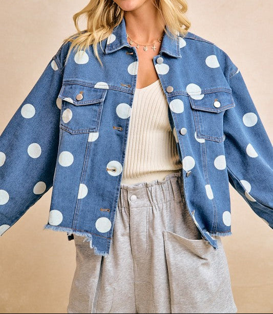 Woman wearing a blue denim jacket with white polka dots on a beige background