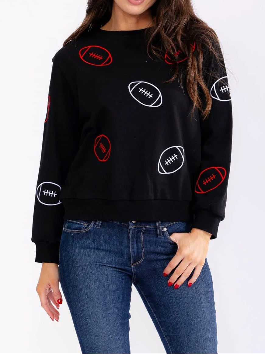Woman wearing a black sweater with football graphics on a white background