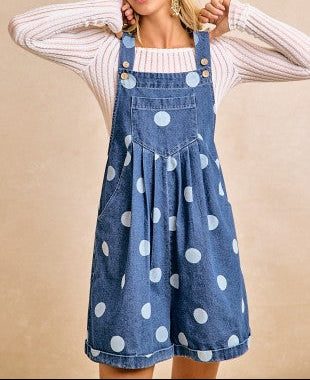 Woman wearing a blue polka dot denim dress against a beige background