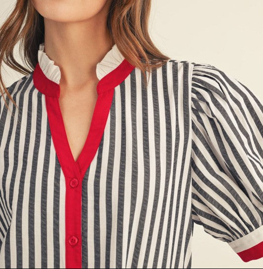 Woman wearing a striped shirt with red accents on a plain background