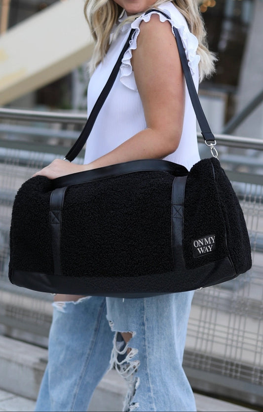 Woman carrying a black bag with 'Onmyway' branding in an urban setting.