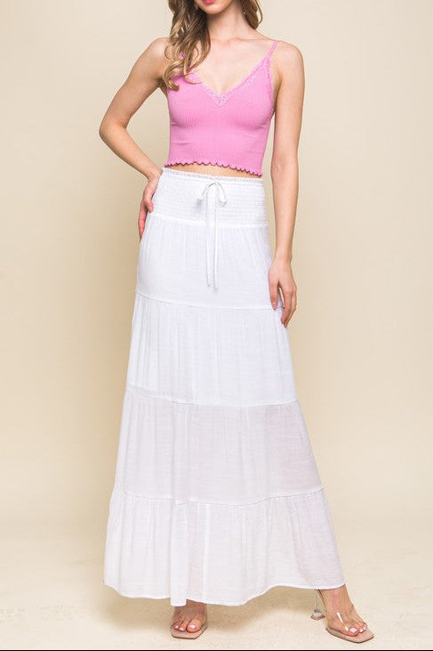 Woman wearing a pink top and white skirt against a beige background
