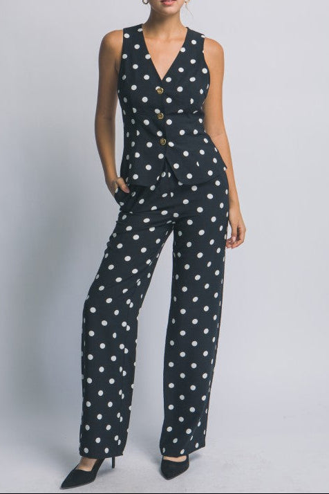 Woman wearing a black polka dot jumpsuit on a plain background