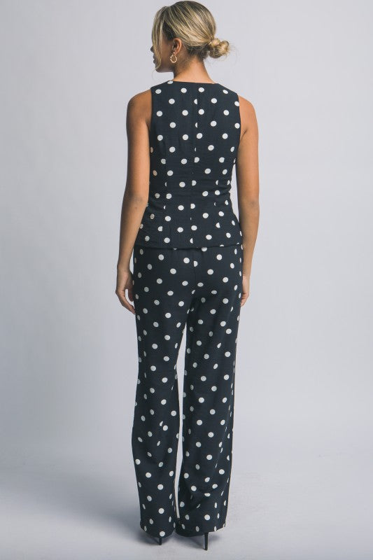 Woman wearing a black polka dot jumpsuit on a gray background