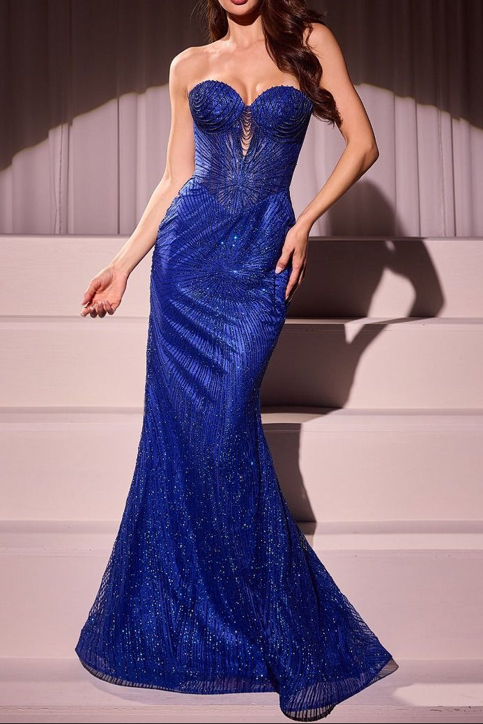 Woman in a blue evening gown standing on steps with a neutral background