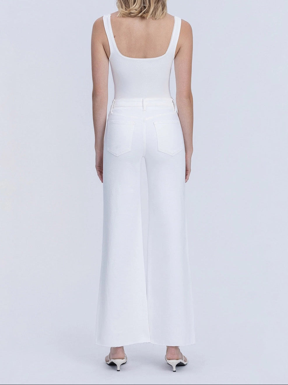 Woman wearing a white sleeveless jumpsuit on a light gray background