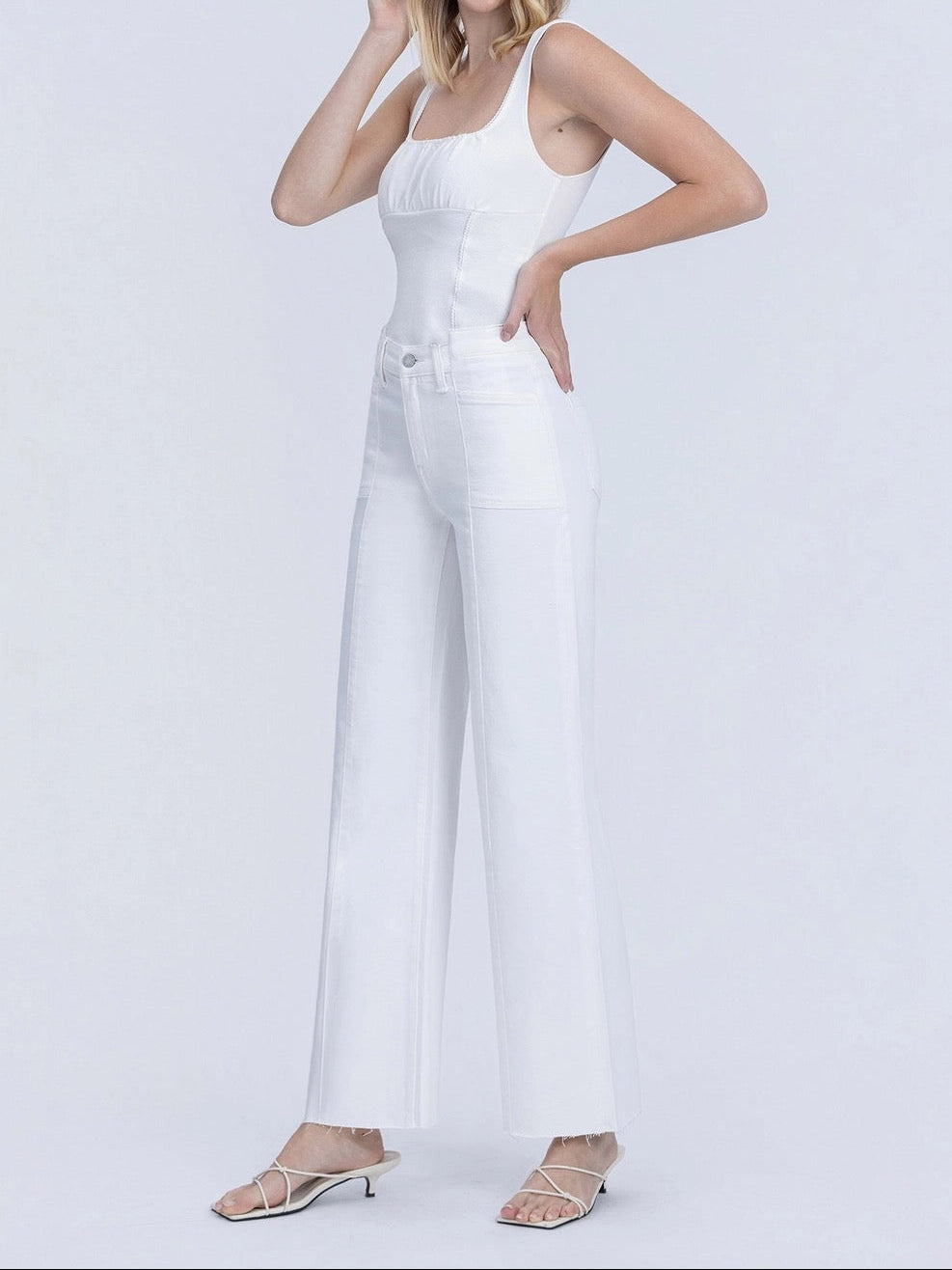 Woman wearing a white jumpsuit on a light gray background