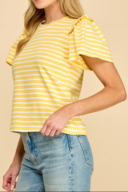 Woman wearing a yellow striped shirt with ruffled sleeves on a beige background