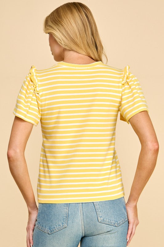 Woman wearing a yellow and white striped shirt with ruffled sleeves on a beige background
