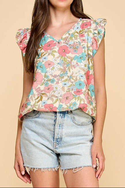 Woman wearing a floral top and denim shorts on a beige background
