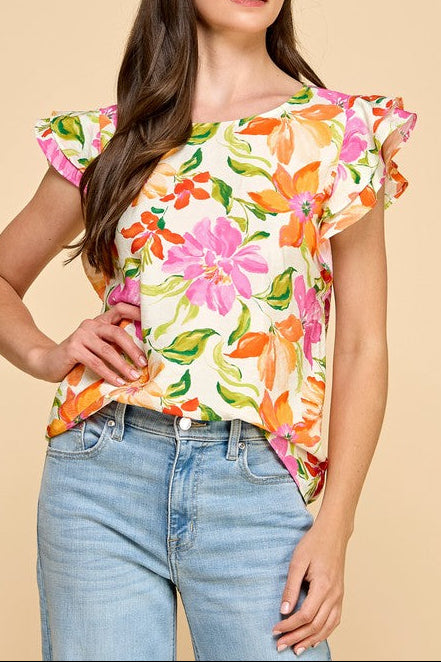 Woman wearing a colorful floral top and jeans on a beige background