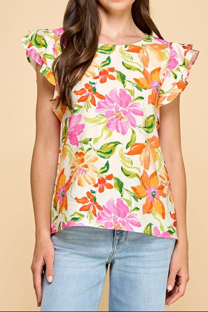 Woman wearing a colorful floral top against a beige background