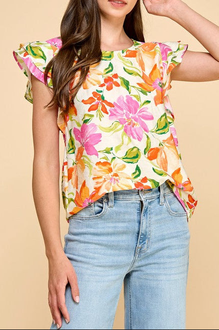 Woman wearing a colorful floral top and blue jeans on a beige background
