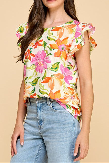 Woman wearing a colorful floral top and jeans on a beige background