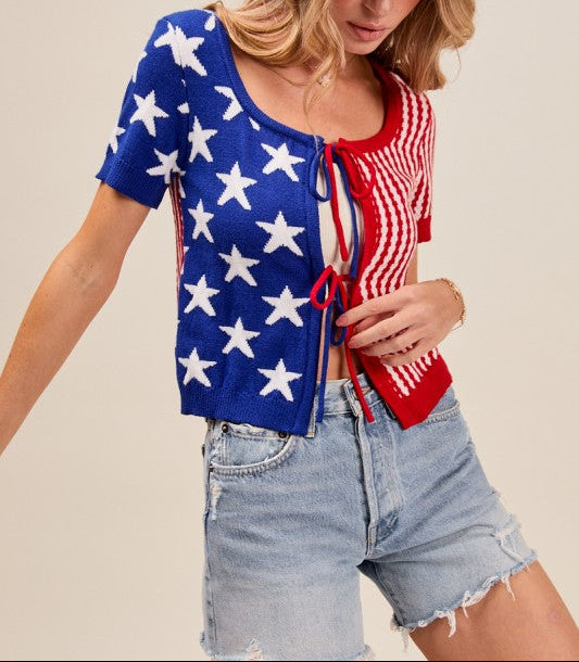 Woman wearing a blue and white star-patterned top with denim shorts and a pink hat.