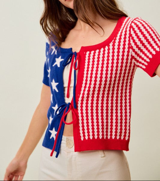 Woman wearing a red, white, and blue top with a patterned design on a plain background