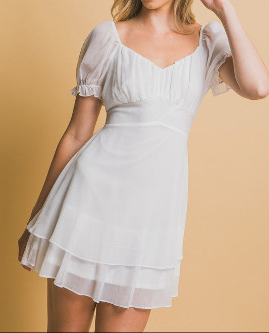 Woman wearing a white dress against a beige background