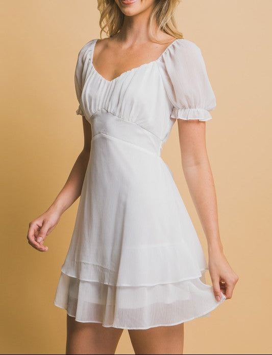 Woman wearing a white dress against a beige background