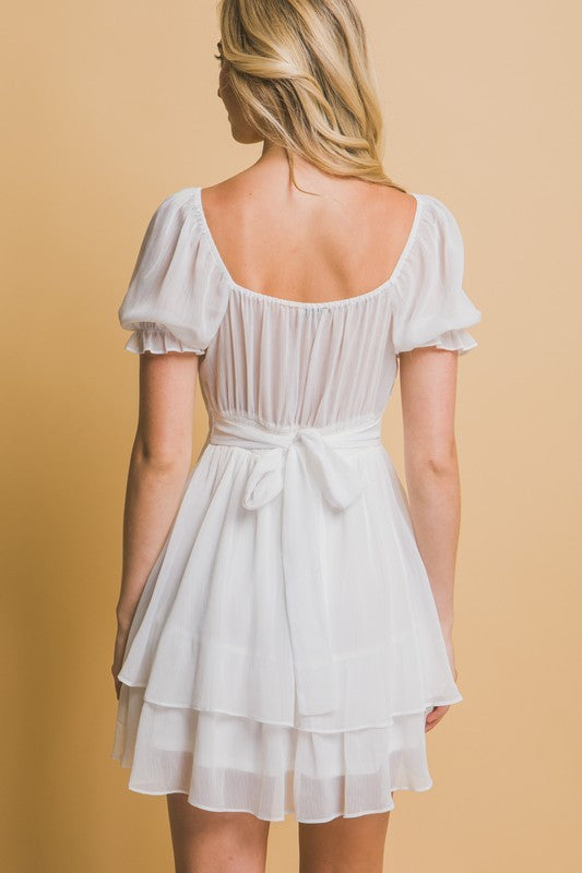 White dress with ruffled sleeves on a beige background