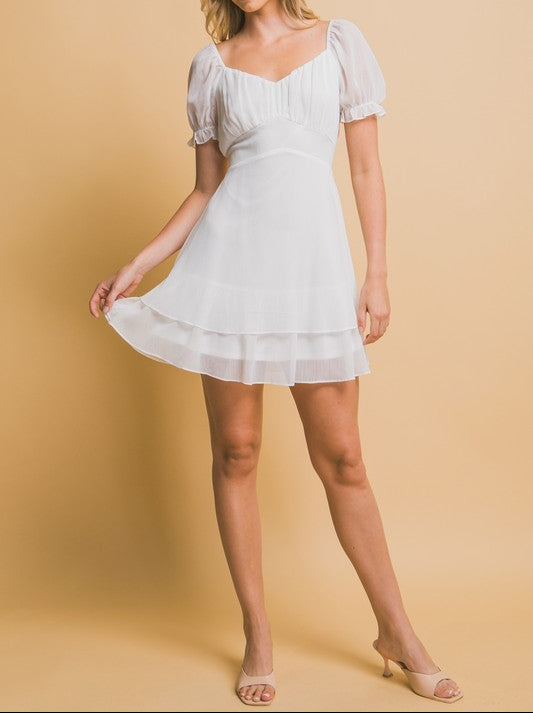 Woman wearing a white dress against a beige background