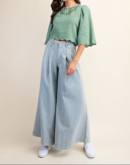 Woman wearing a green top and light blue jeans on a beige background