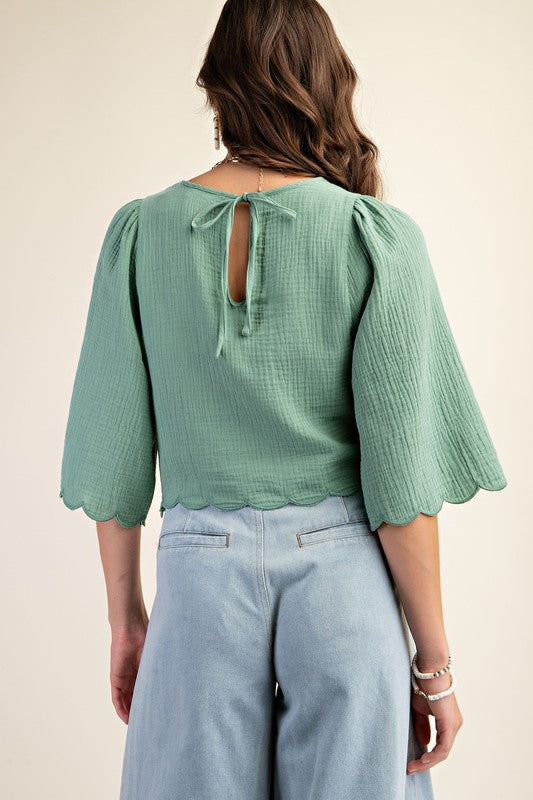 Woman wearing a green blouse with a cut-out back design on a beige background