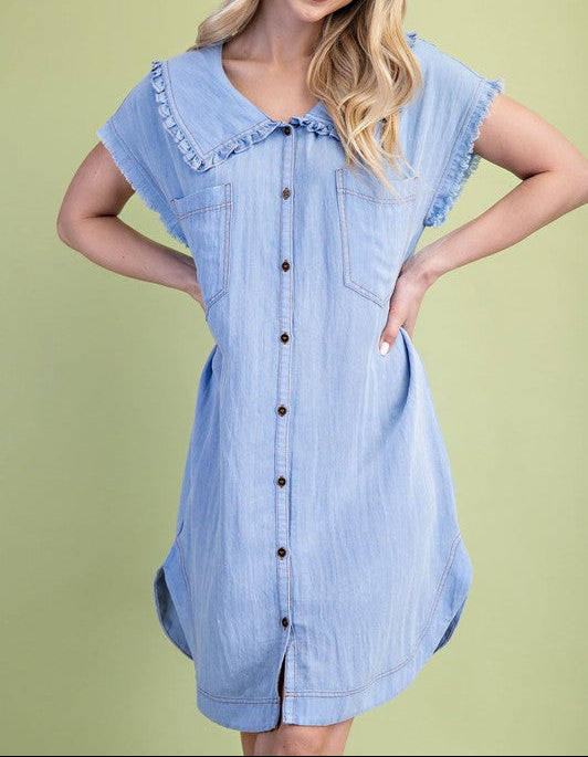 Woman wearing a light blue denim dress against a green background