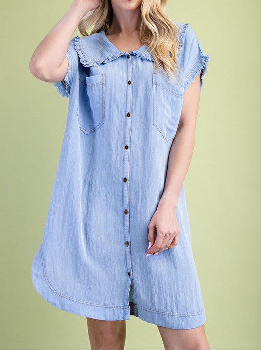 Woman wearing a light blue denim dress against a green background