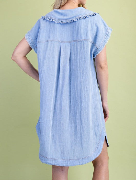 Light blue denim dress worn by a person on a green background