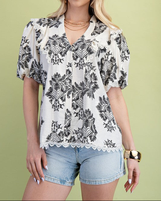 Woman wearing a floral blouse and denim shorts against a green background