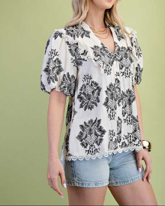 Woman wearing a floral blouse and denim shorts against a green background