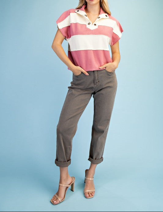 Woman wearing a colorful striped shirt and gray pants on a light blue background